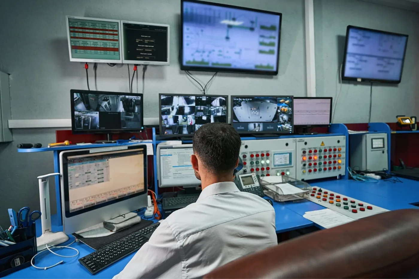 Controlekamer met een operator aan een console vol schermen en bedieningspanelen