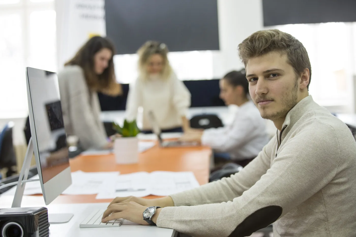 Medewerker aan een bureau in een kantoortuin met collega’s op de achtergrond